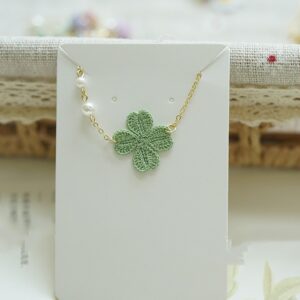 Handmade micro-crochet four-leaf clover bracelet with pearl accents, delicate crochet jewelry from a crochet bracelets supplier.
