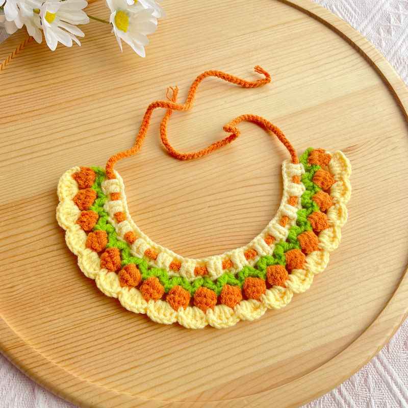 Handcrafted crochet pet necklace featuring orange and green floral designs, perfect as a stylish pet accessory.